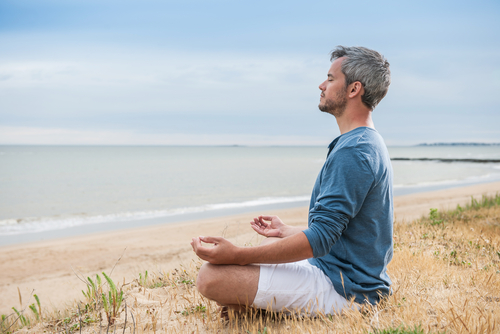 man meditating on beach by Jack Frog shutterstock_249383902